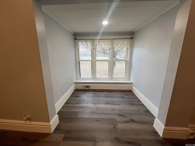 unfurnished dining area featuring baseboards, wood finished floors, visible vents, and crown molding