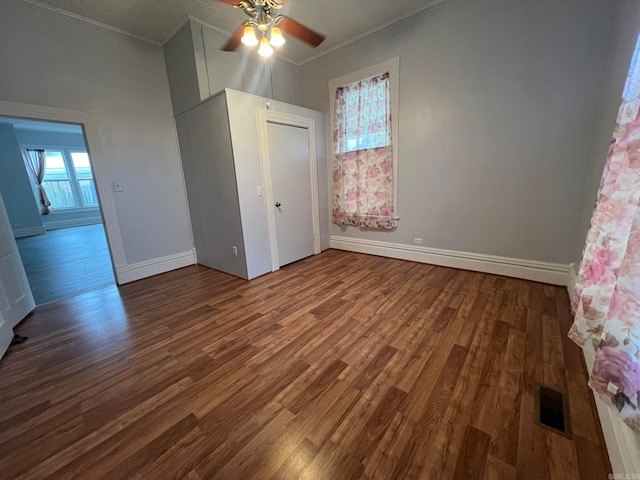 unfurnished bedroom with dark wood-style floors, baseboards, visible vents, and a ceiling fan