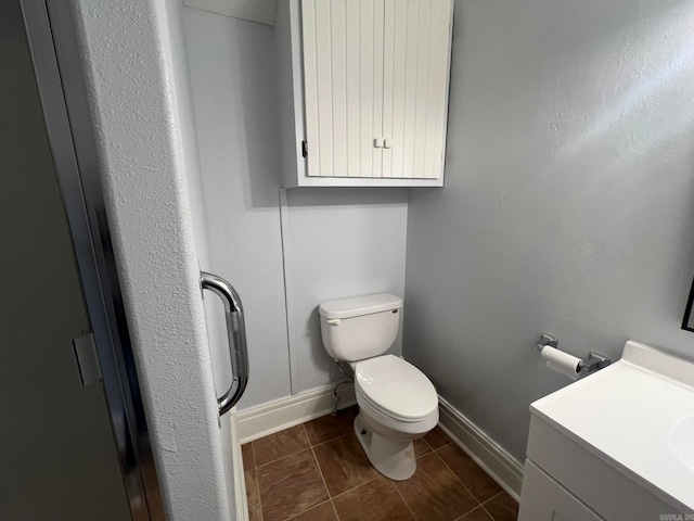 bathroom with baseboards, vanity, and toilet