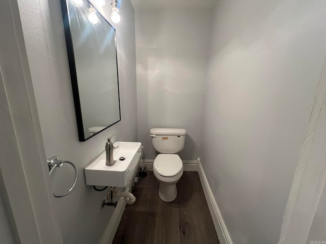 bathroom featuring a sink, wood finished floors, toilet, and baseboards