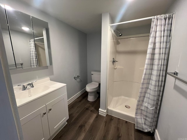 bathroom with a shower with shower curtain, toilet, vanity, wood finished floors, and baseboards