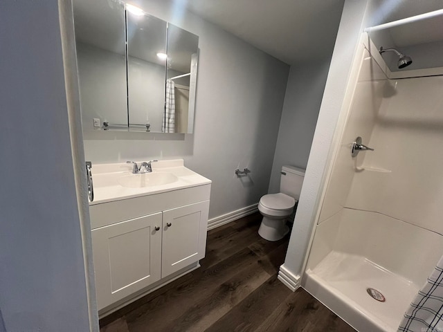 full bathroom featuring toilet, a stall shower, vanity, wood finished floors, and baseboards