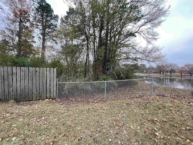 view of yard featuring a water view and a fenced backyard