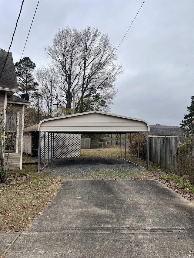 view of car parking featuring driveway, fence, and a detached carport