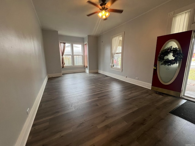 entrance foyer featuring ceiling fan, ornamental molding, dark wood-style flooring, and baseboards