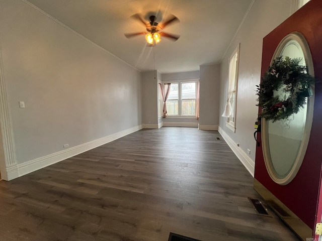 unfurnished room featuring baseboards, visible vents, dark wood finished floors, and a ceiling fan