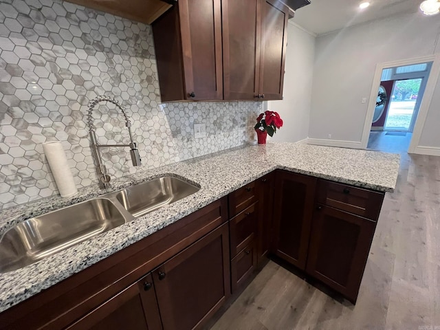 kitchen featuring a sink, a peninsula, decorative backsplash, and wood finished floors