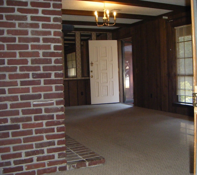 interior space featuring beamed ceiling, carpet floors, wooden walls, and an inviting chandelier