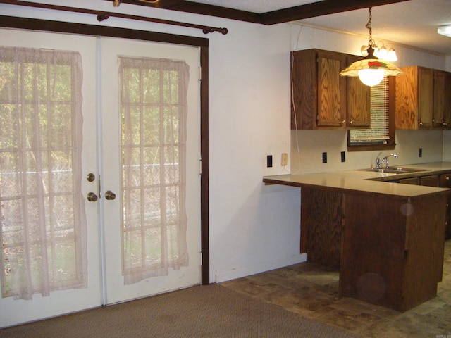 kitchen with pendant lighting, kitchen peninsula, sink, and ornamental molding