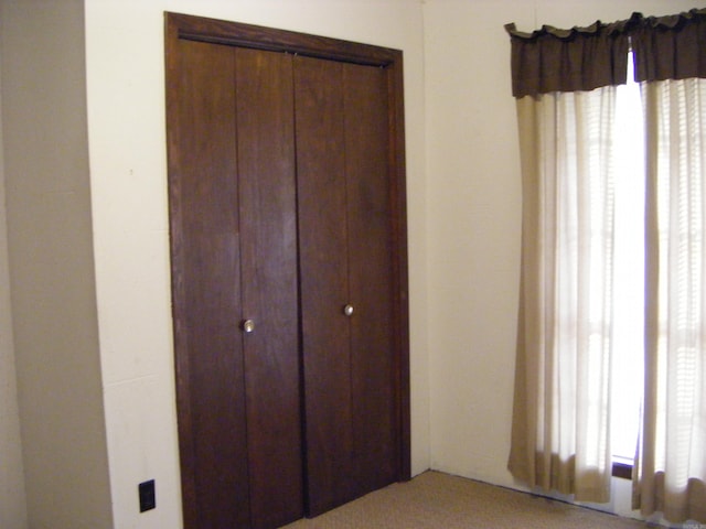 unfurnished bedroom with a closet, multiple windows, and light colored carpet