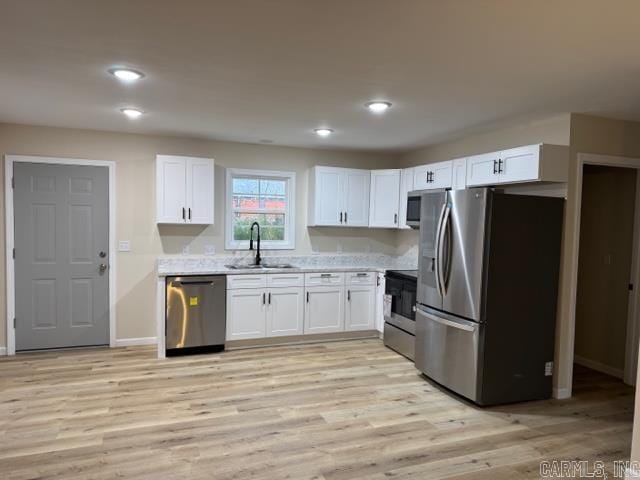 kitchen featuring white cabinetry, sink, stainless steel appliances, and light hardwood / wood-style floors