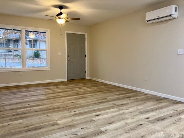 empty room featuring a wall mounted air conditioner, ceiling fan, and light hardwood / wood-style flooring