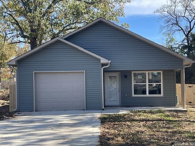 view of front of house featuring driveway, an attached garage, and fence