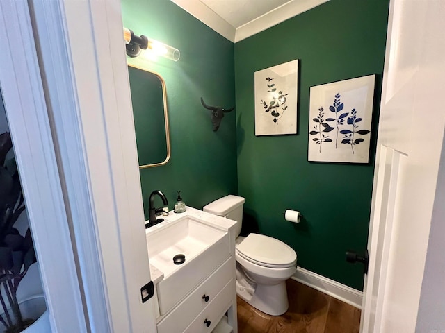 bathroom with vanity, toilet, wood-type flooring, and crown molding