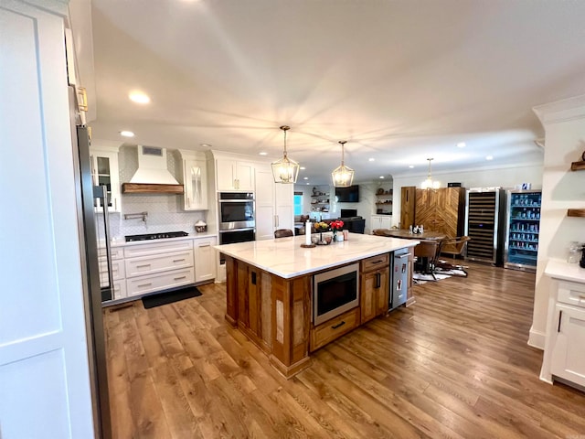 kitchen featuring a center island, stainless steel appliances, premium range hood, white cabinets, and hardwood / wood-style flooring