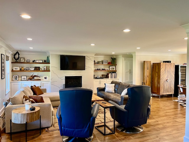 living room featuring a fireplace, light wood-type flooring, and crown molding