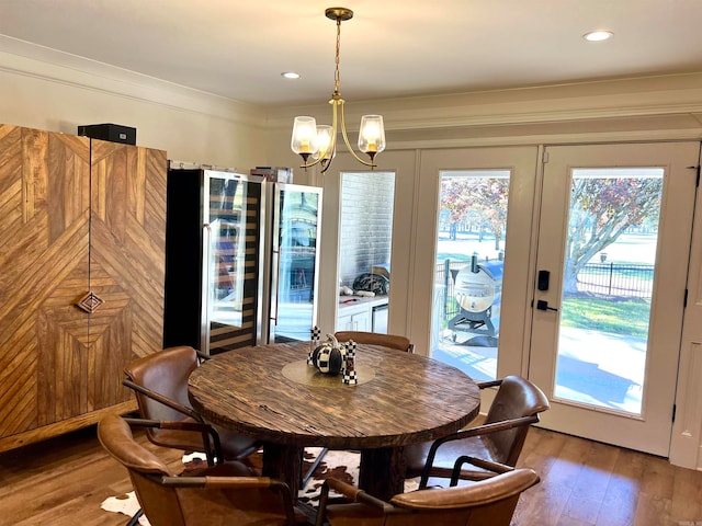 dining room with wood-type flooring, crown molding, beverage cooler, and a notable chandelier