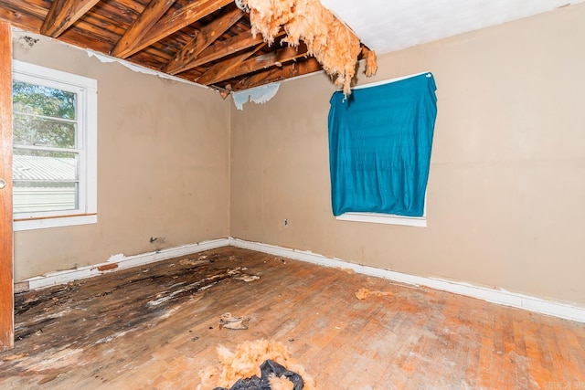 unfurnished room featuring beamed ceiling and hardwood / wood-style floors