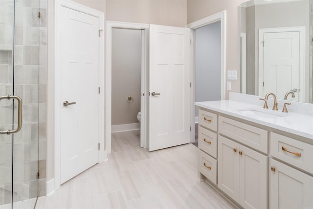 bathroom featuring a shower with door, vanity, and toilet