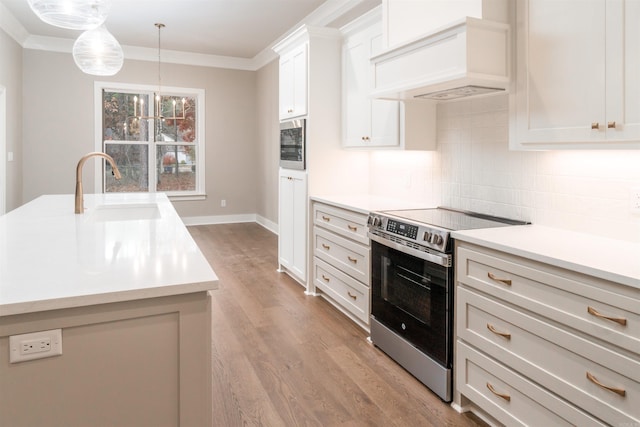 kitchen featuring pendant lighting, stainless steel electric range, sink, light hardwood / wood-style floors, and custom range hood