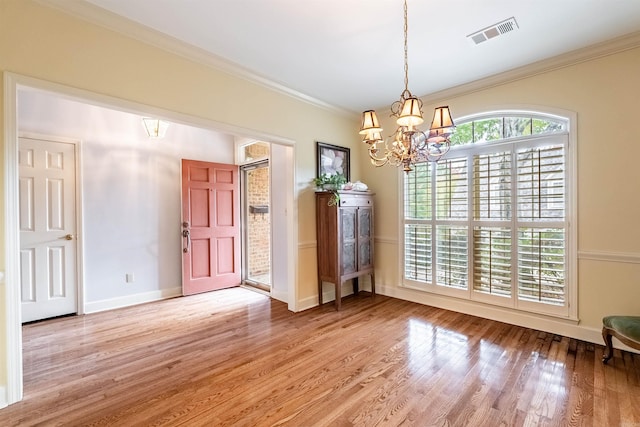 unfurnished dining area featuring hardwood / wood-style flooring, ornamental molding, and an inviting chandelier