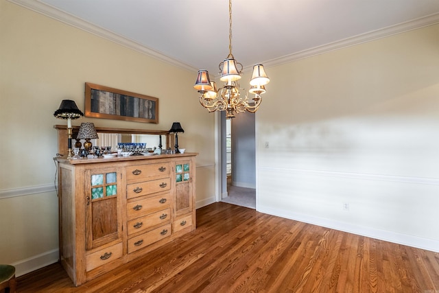 unfurnished dining area with dark hardwood / wood-style floors, ornamental molding, and an inviting chandelier