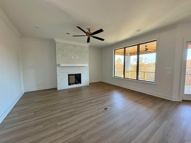 unfurnished living room featuring a high end fireplace, hardwood / wood-style flooring, ceiling fan, and ornamental molding