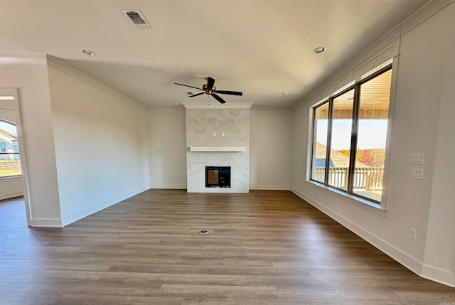 unfurnished living room featuring a fireplace, hardwood / wood-style flooring, ceiling fan, and ornamental molding