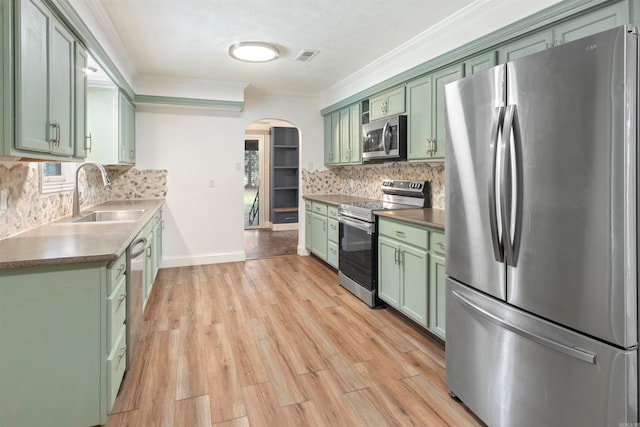 kitchen featuring tasteful backsplash, light hardwood / wood-style flooring, crown molding, appliances with stainless steel finishes, and green cabinetry