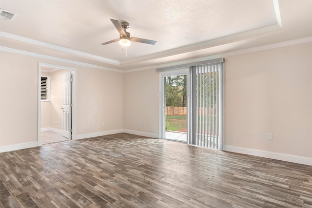 empty room with dark wood-type flooring, a raised ceiling, ceiling fan, ornamental molding, and a textured ceiling