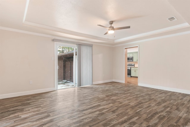 unfurnished room with a tray ceiling, crown molding, and dark hardwood / wood-style floors