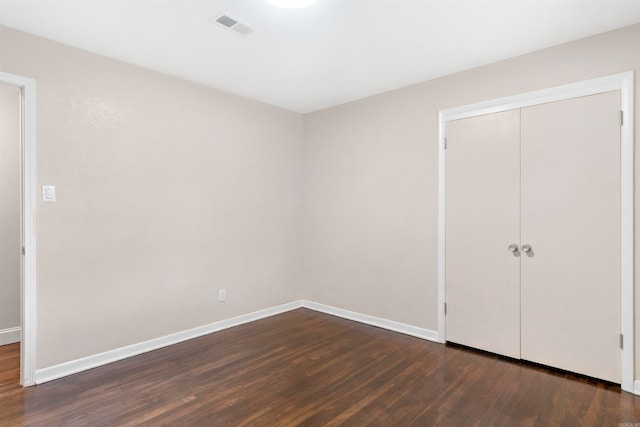 unfurnished bedroom featuring dark hardwood / wood-style flooring and a closet