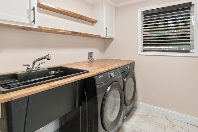 laundry area featuring washing machine and clothes dryer, sink, cabinets, and ornamental molding