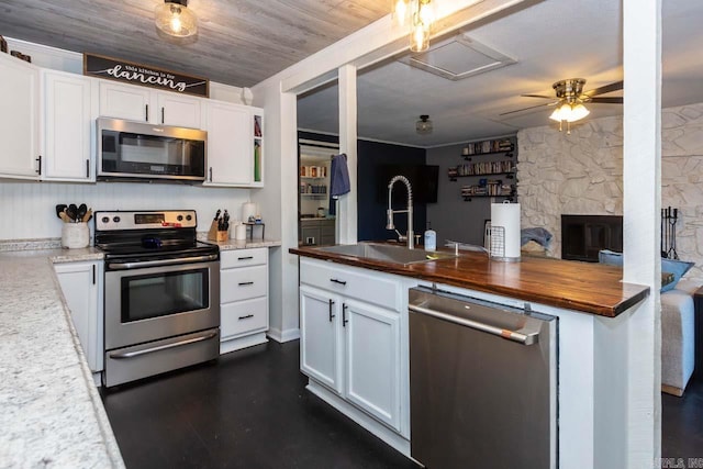 kitchen featuring sink, a fireplace, white cabinets, wood ceiling, and appliances with stainless steel finishes