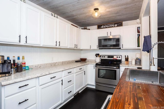 kitchen with light stone countertops, white cabinetry, stainless steel appliances, and wooden ceiling