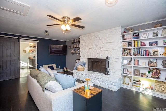 living room with a fireplace, dark hardwood / wood-style flooring, a barn door, and ceiling fan