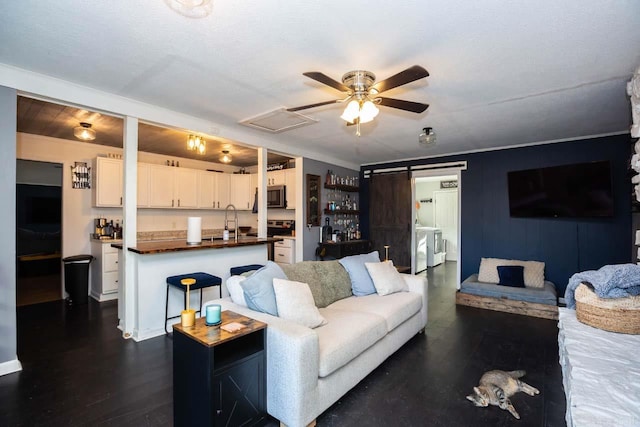 living room with ceiling fan, sink, dark hardwood / wood-style flooring, washer and dryer, and ornamental molding