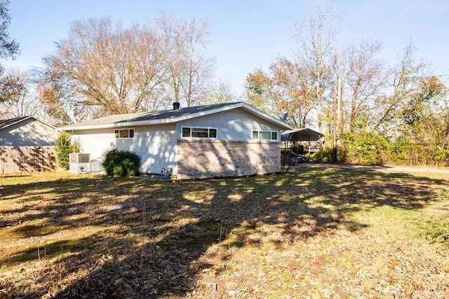 back of house featuring a carport and a lawn