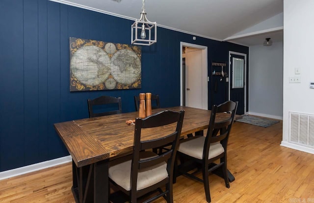 dining room featuring crown molding, light hardwood / wood-style flooring, and vaulted ceiling