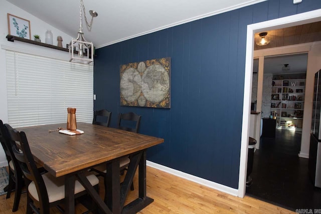 dining space featuring wood-type flooring, crown molding, and lofted ceiling