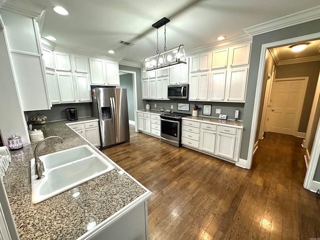 kitchen with sink, dark wood-type flooring, stainless steel appliances, pendant lighting, and white cabinets