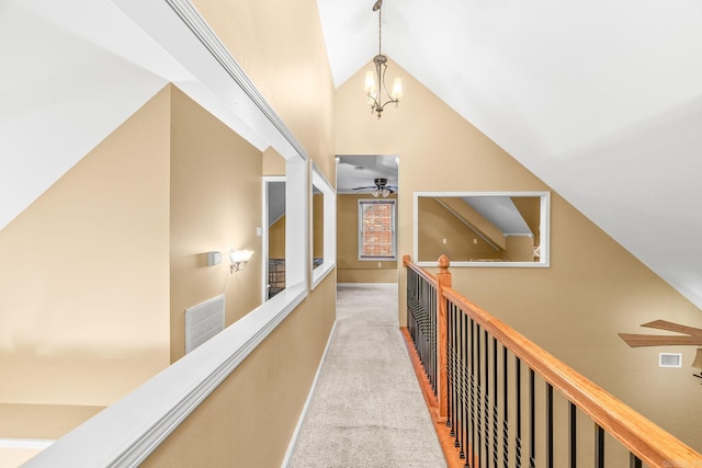 corridor featuring light colored carpet, high vaulted ceiling, and an inviting chandelier