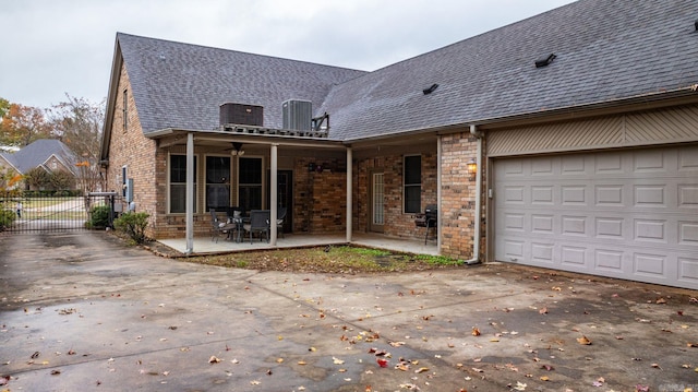 back of house featuring a porch, cooling unit, a garage, and a patio area