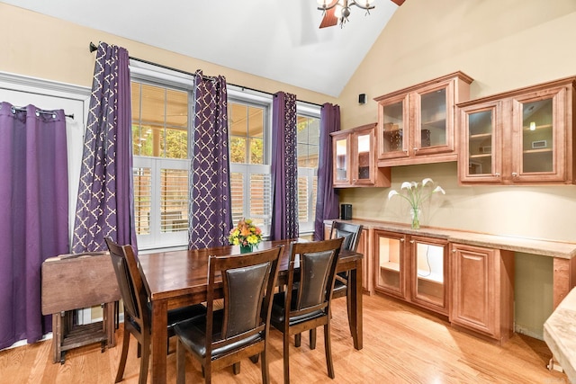 dining space with ceiling fan, vaulted ceiling, and light hardwood / wood-style flooring