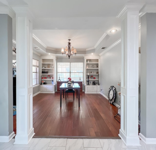 dining room with hardwood / wood-style floors, a raised ceiling, and ornate columns