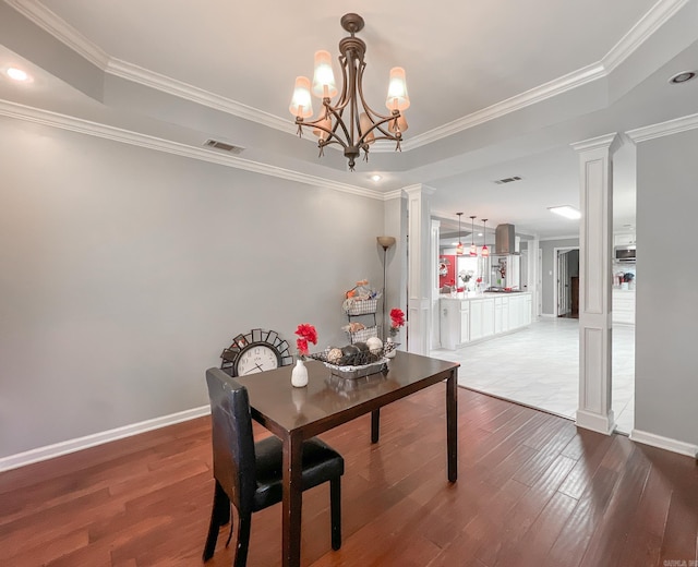 dining room with decorative columns, crown molding, and wood-type flooring