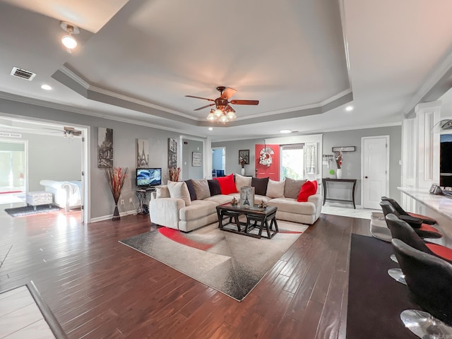 living room featuring crown molding, a raised ceiling, and dark wood-type flooring