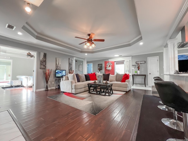 living room featuring hardwood / wood-style flooring, ceiling fan, crown molding, and a tray ceiling