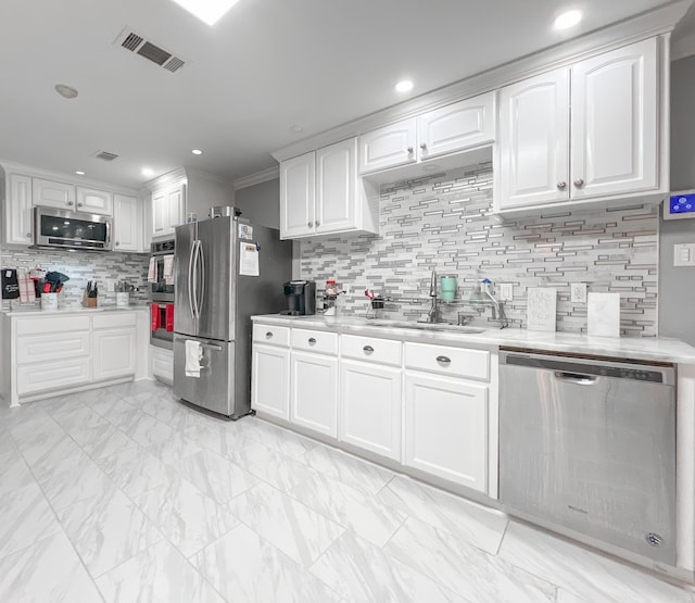 kitchen with appliances with stainless steel finishes, white cabinetry, ornamental molding, and sink