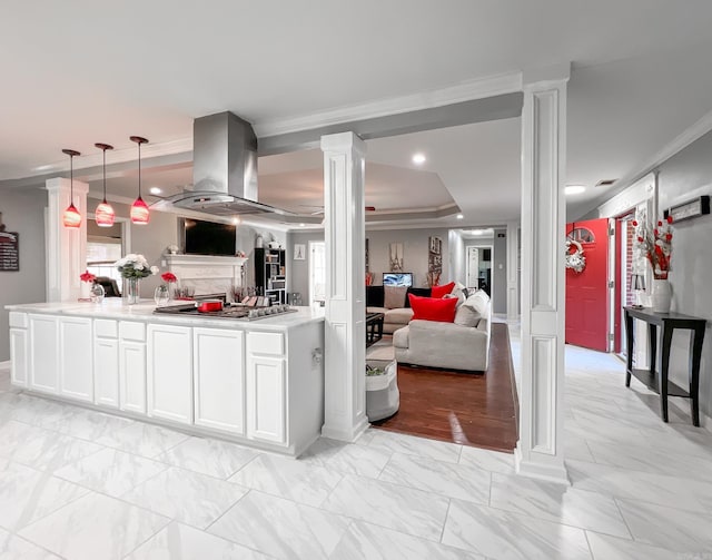 kitchen featuring white cabinets, hanging light fixtures, ornate columns, ornamental molding, and island range hood